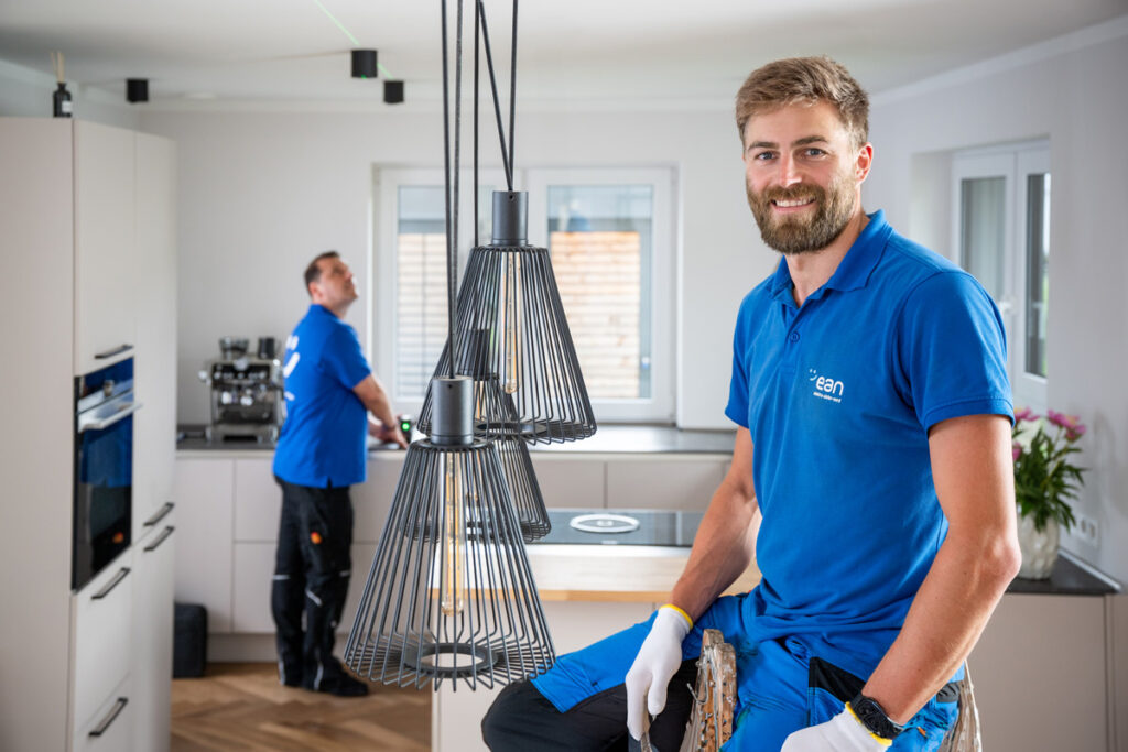 elektriker arbeitet in der Küche ein anderer lehnt am Tisch